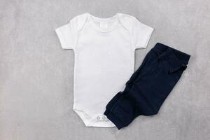 White baby girl or boy bodysuit mockup flat lay with dark blue panties on the gray concrete background. Design onesie template, print presentation mock up. Top view. photo