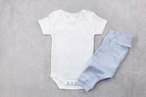 White baby girl or boy bodysuit mockup flat lay with blue panties on the gray concrete background. Design onesie template, print presentation mock up. Top view. photo