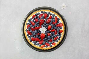 Delicious blueberry and strawberry tart with whipped cream and mascarpone on a light gray concrete background. Top view. photo