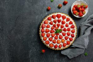Delicious strawberry tart with whipped cream and mascarpone on a dark concrete background. Top view. Copy space. photo