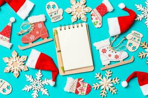 Top view of notebook with Christmas decorations and Santa hats on blue background. Happy holiday concept photo