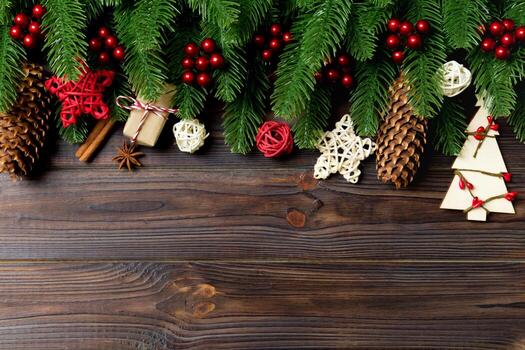 Top view of frame made of fir tree branches and holiday decorations on wooden background. Christmas concept with empty space for your design photo