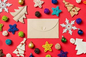 Top view of craft envelope on red background made of holiday decorations and toys. Christmas ornament concept photo