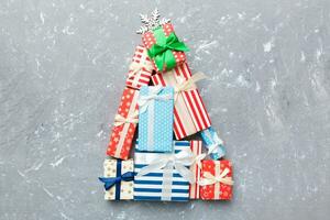 Christmas tree made of beautifuly wrapped presents on colored background, view from above. New Year gift box minimal concept with copy space photo