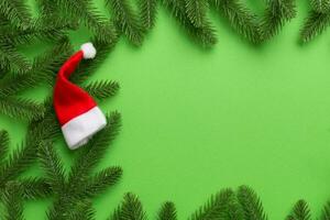 Christmas holiday composition. fir branches with santa hat on green background. New Year, winter concept. Flat lay, top view, copy space photo