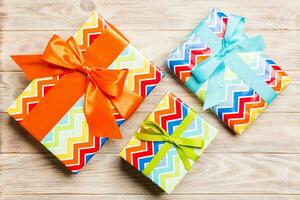 paper gift box with colored ribbon on orange wood background. top view with copy space Christmas holiday concept photo