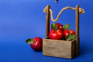 maduro rojo manzanas en de madera caja. en un blanco de madera antecedentes foto