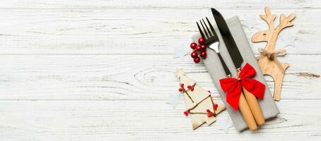 New year Banner set of fork and knife on napkin. Top view of christmas decorations and reindeer on wooden background. Holiday family dinner concept with empty space for your design photo