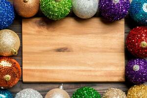 Top view of empty plate surrounded with colorful baubles on wooden background. New Year decorations. Christmas Eve concept photo