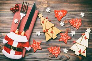 Top view of fork and knife tied up with ribbon on napkin on wooden background. Close up of christmas decorations and New Year tree. Happy holiday concept photo