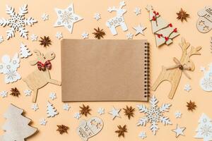 Festive decorations and toys on orange background. Top view of notebook. Merry Christmas concept photo