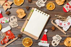 Top view of notebook on wooden background made of Christmas decorations. New Year concept photo