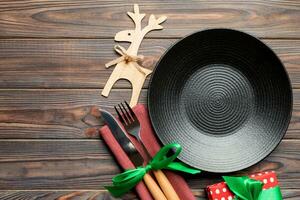 Top view of plate, fork and knife served on Christmas decorated wooden background. New Year Eve concept with copy space photo