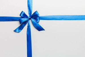 Top view of blue ribbon rolled and blue bow isolated on colored background. Flat lay with copy space photo