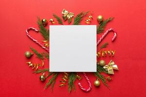 Flat lay Christmas composition. square Paper blank, pine tree branches, christmas decorations on Colored background. Top view, copy space for text photo