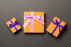 Top view Christmas present box with purple and pink bow on black background photo