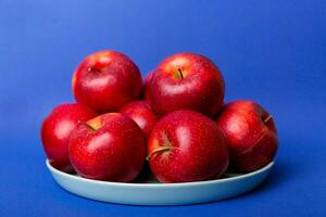 juicy red apples in a bowl or plate on the table top view. Copy space photo