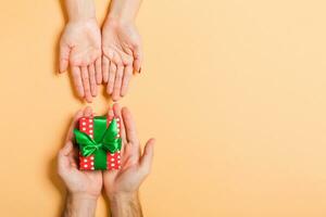 Top view of a man holding and giving a gift to a woman on colorful background. Receiving a present. Close up of holiday concept photo