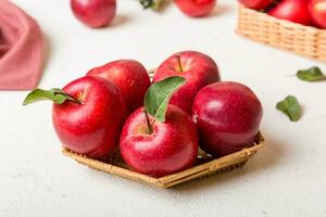 Ripe garden apple fruits with leaves in basket on wooden table. Top view flat lay with copy space photo