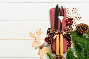 Top view of flatware tied up with ribbon on napkin on wooden background. Christmas decorations and reindeer with empty space for your design. New Year holiday concept photo