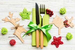 Top view of new year utensils on napkin with holiday decorations and reindeer on wooden background. Close up of christmas dinner concept photo