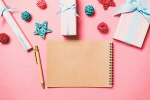 Top view of notebook on pink background made of Christmas decorations. New Year time concept photo