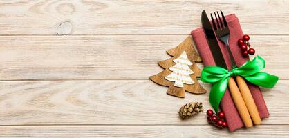 Top view of fork and knife tied up with ribbon on napkin on wooden background. Christmas decorations and New Year tree. Banner Happy holiday concept with empty space for your design photo