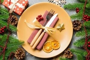 Top view of cutlery and plate on festive cement background. New Year family dinner concept. Fir tree and Christmas decorations photo