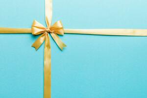 Top view of gold ribbon rolled and yellowbow isolated on colored background. Flat lay with copy space photo