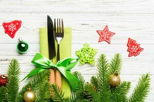 Top view of christmas decorations on wooden background. Fork and knife on napkin tied up with ribbon and empty space for your design. New year pattern concept photo