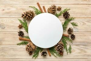 Flat lay Christmas composition. Round Paper blank, pine tree branches, christmas decorations on Colored background. Top view, copy space for text photo