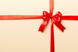 Top view of Red ribbon rolled and red bow isolated on colored background. Flat lay with copy space photo