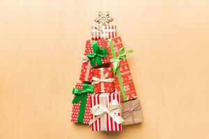 Christmas tree made of beautifuly wrapped presents on colored background, view from above. New Year gift box minimal concept with copy space photo
