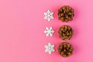 Top view of holiday composition made of pine cones and white snowflakes on colorful background. Winter time and Christmas concept with copy space photo