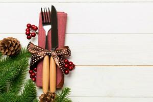 Top view of christmas decorations on wooden background. Fork and knife on napkin tied up with ribbon and empty space for your design. New year pattern concept photo