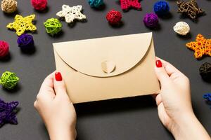 Top view of woman holding an envelope on black background made of holiday decorations. Christmas time concept photo