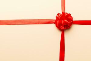 Top view of Red ribbon rolled and red bow isolated on colored background. Flat lay with copy space photo