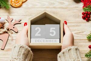 vista superior de manos femeninas sosteniendo un calendario sobre fondo de madera. el veinticinco de diciembre. decoraciones navideñas. concepto de navidad foto