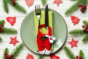 Top view of Christmas dinner on wooden background. Plate, utensil, fir tree and holiday decorations. New Year time concept photo