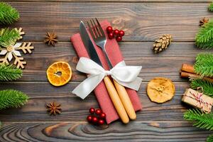 Top view of utensils on festive napkin on wooden background. Christmas decorations with dried fruits and cinnamon. Close up of New year dinner concept photo