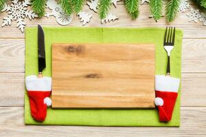 Top view of Christmas dinner on wooden background. Plate, utensil, fir tree and holiday decorations with copy space. New Year time concept photo