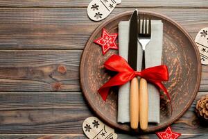 Top view of plate, fork and knife served on Christmas decorated wooden background. New Year Eve concept with copy space photo