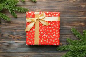 Christmas composition. Christmas gift and fir branches on wooden background. Flat lay, top view, copy space photo