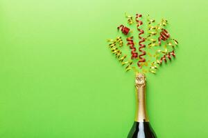 Creative flat lay composition with bottle of champagne and space for text on color background. Champagne bottle with colorful party streamers. holiday or christmas concept photo