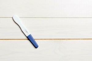 Colored Pregnancy test on wooden background, top view with copy space photo