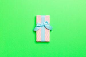 wrapped Christmas or other holiday handmade present in paper with blue ribbon on green background. Present box, decoration of gift on colored table, top view with copy space photo