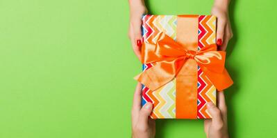 Top view of a man and a woman congratulating each other with a gift on colorful background. Surprise for a holiday concept. Copy space photo