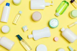 grupo de botellas de plástico para el cuidado del cuerpo composición plana con productos cosméticos sobre fondo amarillo espacio vacío para su diseño. conjunto de envases cosméticos blancos, vista superior con espacio de copia foto