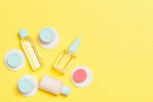 conjunto de botellas cosméticas de tamaño de viaje sobre fondo amarillo. endecha plana de tarros de crema. vista superior del concepto de estilo de cuidado corporal foto