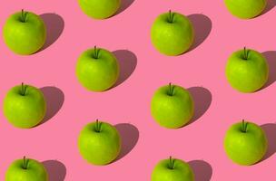 Trendy fruit pattern made of green apples on light pastel pink background. Minimal layout. Nature summer concept. photo